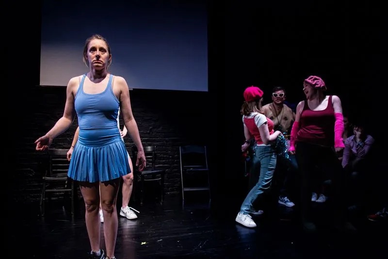 Grace Fennell mid-sketch in a blue tennis dress, four castmates behind her.