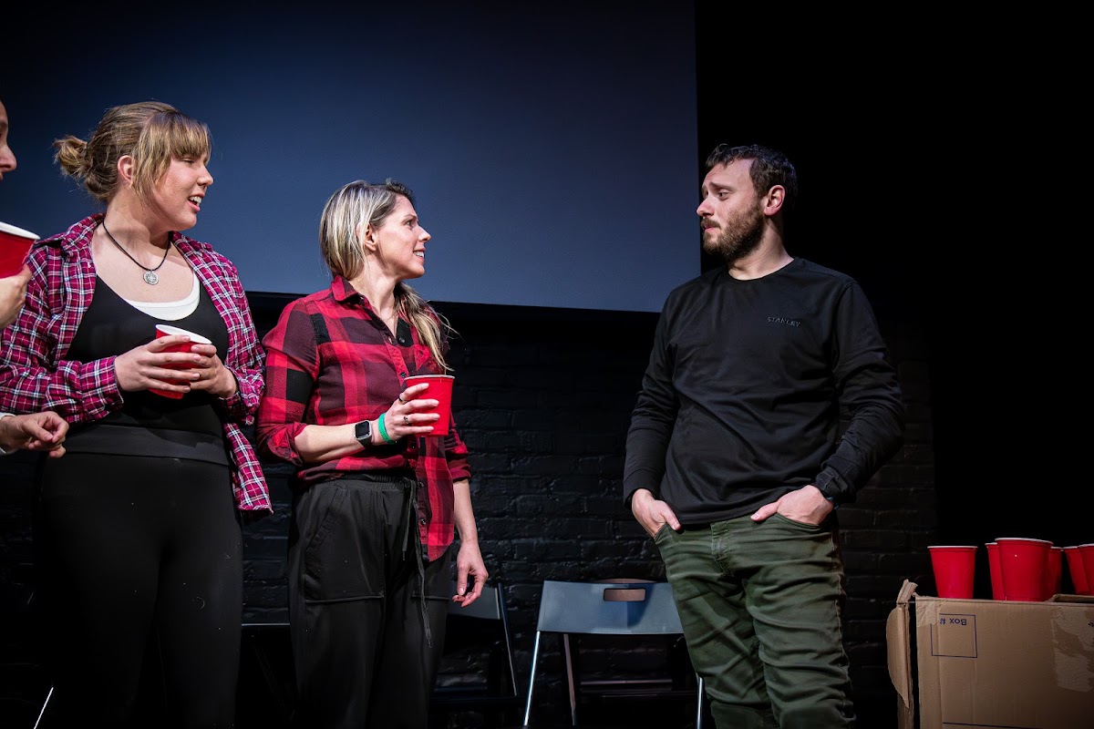 Four performers crowded into a scene, all talking at once.